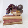 Golden earrings displayed on books and grapes. Made by Jesse Ball at Jupiter's Grace
